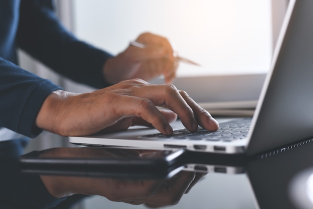 Close up van man aan het werk op laptopcomputer op kantoor tafel