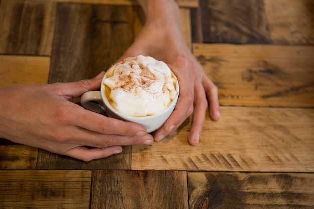 Close-up van man handen met koffiekopje aan tafel in cafetaria