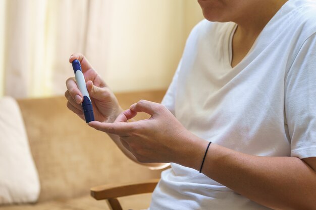 Close up van man handen met lancet op vinger om bloedsuikerspiegel te controleren met glucosemeter