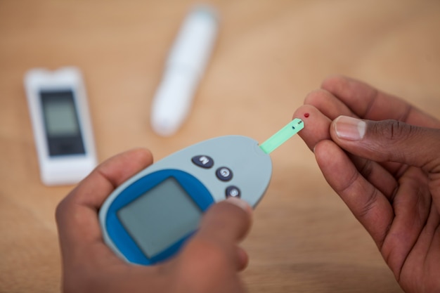 Close-up van man handen testen bloedsuiker met glucometer