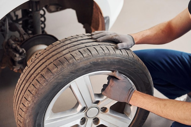 Close-up van man in werkuniform met autowiel binnenshuis Conceptie van autoservice