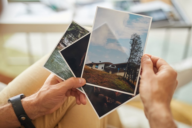 Close-up van man met foto's met prachtige landschappen in zijn handen