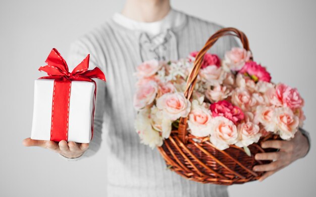 close-up van man met mand vol bloemen en geschenkdoos.