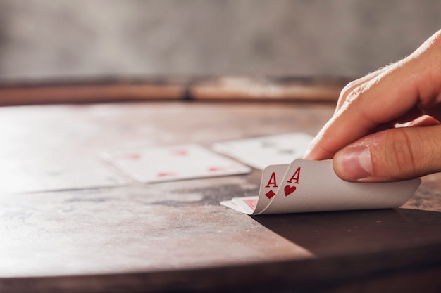 Close-up van man's hand die zijn kaarten met twee azen toont tijdens het spelen van poker op vat