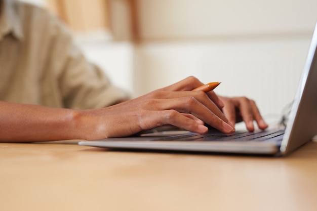 Close-up van man zit aan de tafel en typen op laptopcomputer die hij online werkt