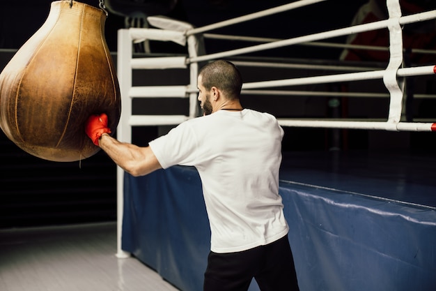Close-up van mannelijke bokser boksen in bokszak, slow-motion.