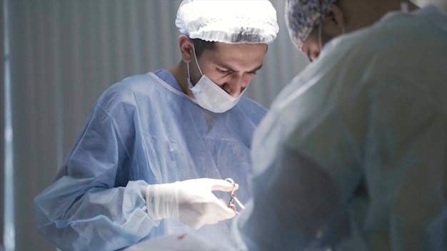 Close-up van mannelijke chirurgen aan het werk actie zijbeeld van geconcentreerde artsen die naar beneden kijken naar de