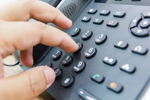 Close-up van mannelijke hand die telefoonontvanger houdt terwijl het draaien van een telefoonnummer