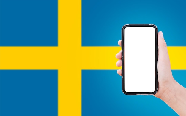 Close-up van mannelijke hand met smartphone met blanco op het scherm op de achtergrond van de vage vlag van Zweden