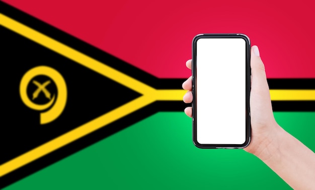 Close-up van mannelijke hand met smartphone met blanco scherm op de achtergrond van wazige vlag van Vanuatu