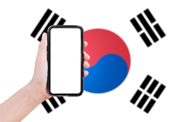 Close-up van mannelijke hand met smartphone met blanco scherm op de achtergrond van wazige vlag van Zuid-Korea