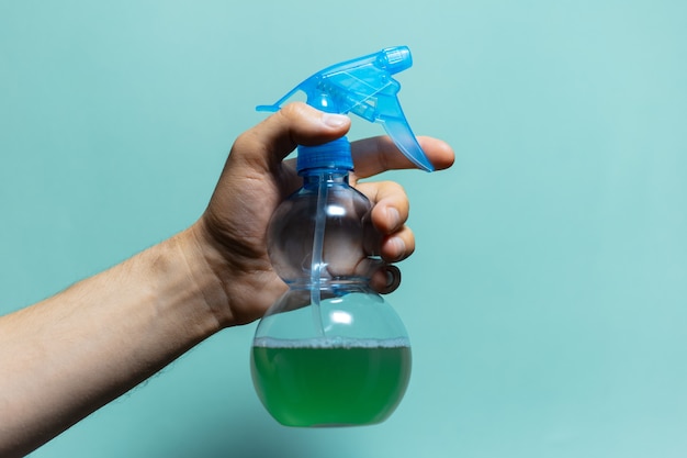 Close-up van mannelijke hand met spuitfles voor het reinigen met blauwe pomp