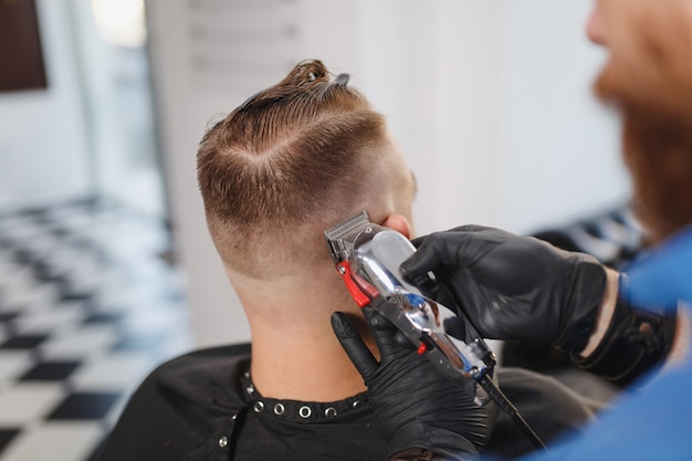 Close up van mannelijke professionele kapper die klant bedient door clipper