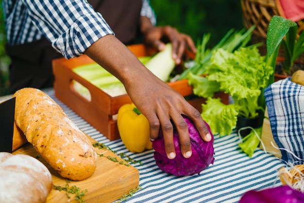 Close-up van mannenhand die biologische groenten op tafel zet in de boerderijmarkt