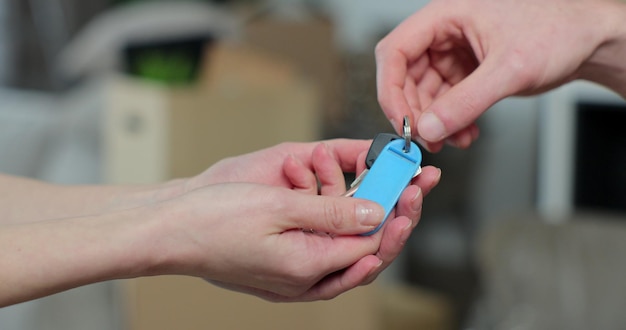 Close up van mannenhand sleutel doorgeven aan vrouw in nieuw appartement man sleutels van nieuw huis overhandigen aan vrouw klant huis verkopen makelaar baan