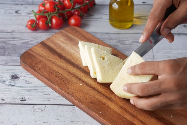 close-up van mans hand snijden kaas op een snijplank