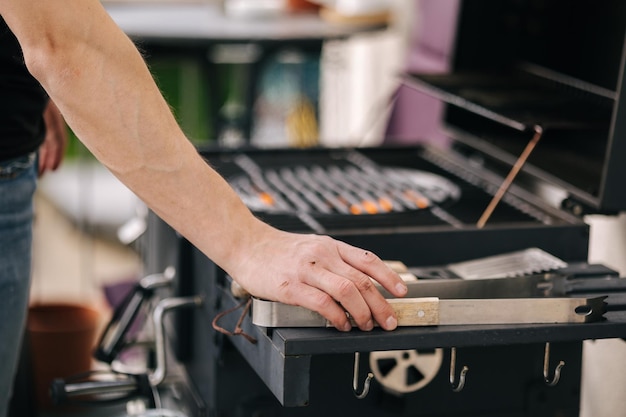 Close-up van mans hand zet metalen grilltang op de zijstandaard