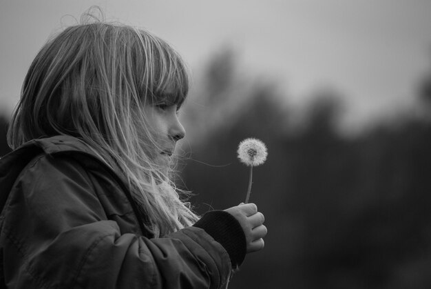 Foto close-up van meisje met bloem tegen de lucht