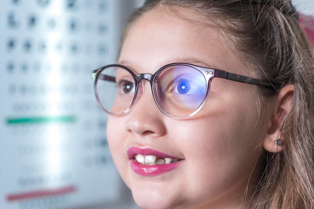 Foto close-up van meisje met bril, ze bezoekt de oogarts om haar zicht te controleren, ze glimlacht visuele gezondheid