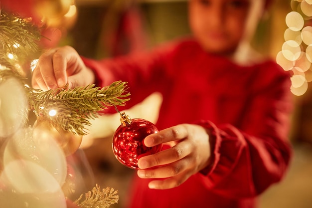 Close up van meisje opknoping ornamenten op kerstboom met fonkelende lichtjes kopieer ruimte