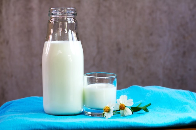 Close-up van melk in fles en glas op blauwe stof