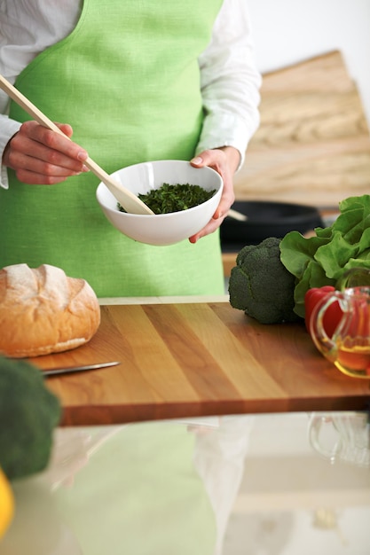 Close-up van menselijke handen die groentensalade in keuken op de glaslijst met bezinning koken. gezonde maaltijd en vegetarisch concept