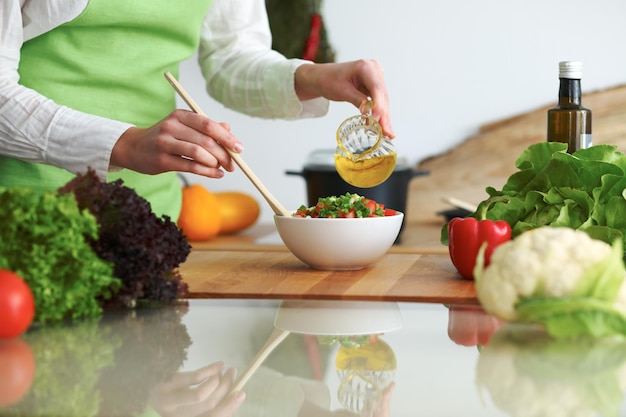 Close-up van menselijke handen die groentensalade in keuken op de glaslijst met bezinning koken. Gezonde maaltijd en vegetarisch concept