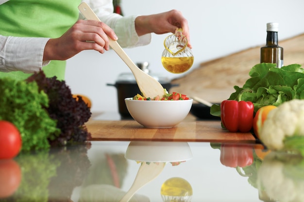 Close-up van menselijke handen die groentensalade in keuken op de glaslijst met bezinning koken. Gezonde maaltijd en vegetarisch concept