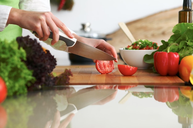 Close-up van menselijke handen die groentensalade in keuken op de glaslijst met bezinning koken