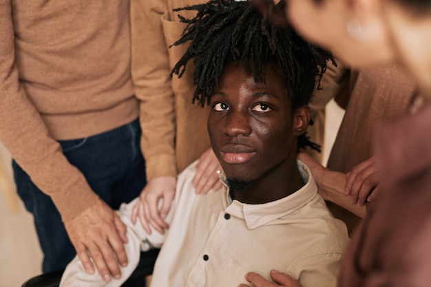 Foto close-up van mensen die jonge man in rolstoel troosten tijdens therapiesessie in steungroep, kopieer ruimte