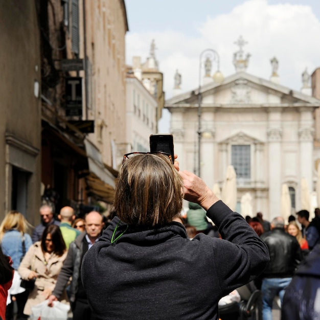 Close-up van mensentoerist op straat in Mantua die foto's maakt van Piazza Sordello met de telefoon Mantua Italy