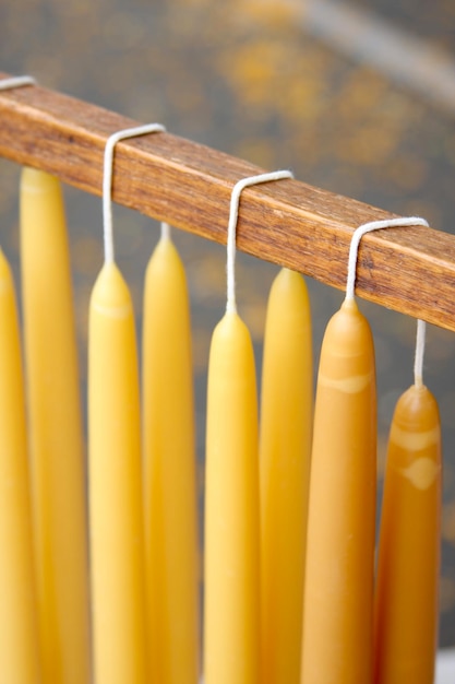 Foto close-up van met de hand gedompelde kaarsen die op een houten staaf hangen