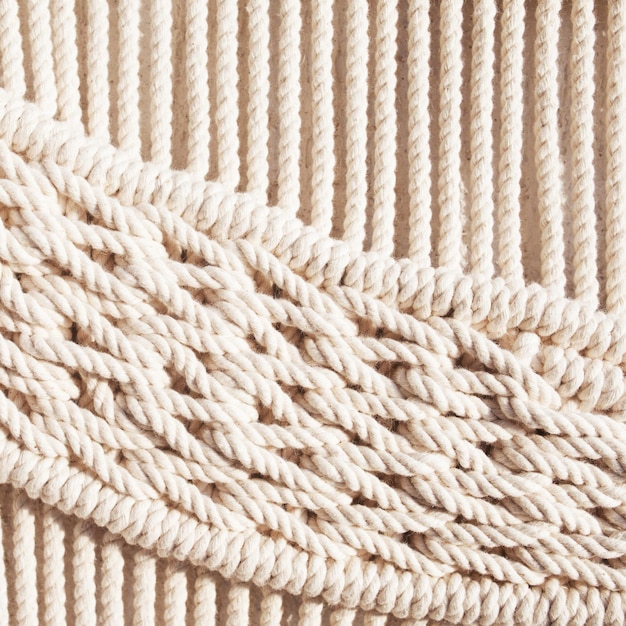 Close-up van met de hand gemaakt macramé structuurpatroon. ECO-vriendelijk modern breiwerk DIY natuurlijk decoratieconcept in het interieur. Handgemaakte macramé 100% katoen. Vrouwelijke hobby.