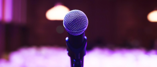 Close up van microfoon op podiumverlichting in concertzaal of vergaderruimte. kopieer ruimtebanner. zachte focus.