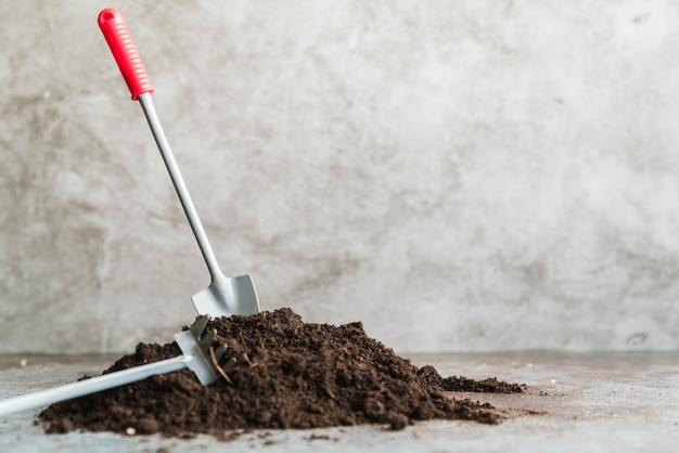 Close-up van mini tuinierende troffel en vork tegen concrete achtergrond