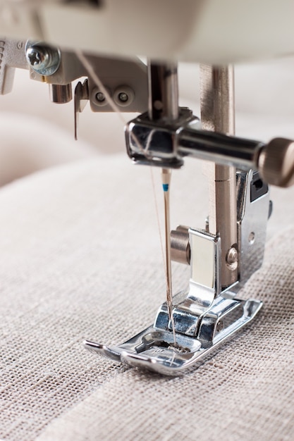 Close-up van moderne naaimachine naaivoet en naald naaien kledingstuk.