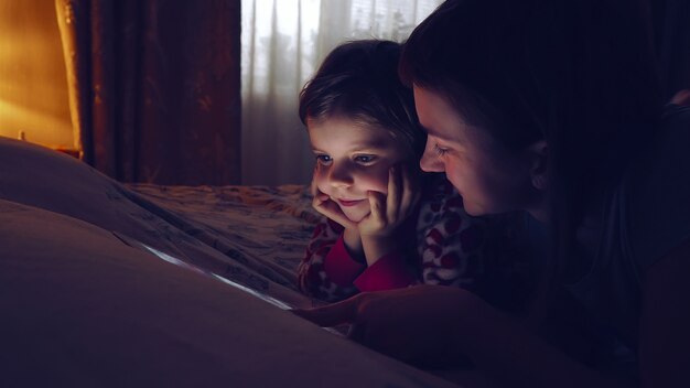 Close-up van moeder en haar kleine dochter het letten op tablet thuis.