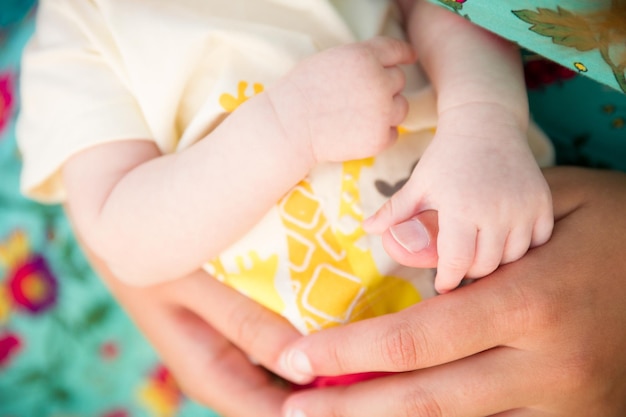 Close-up van moeders handen met klein pasgeboren kind Baby in de handen van zijn moeder