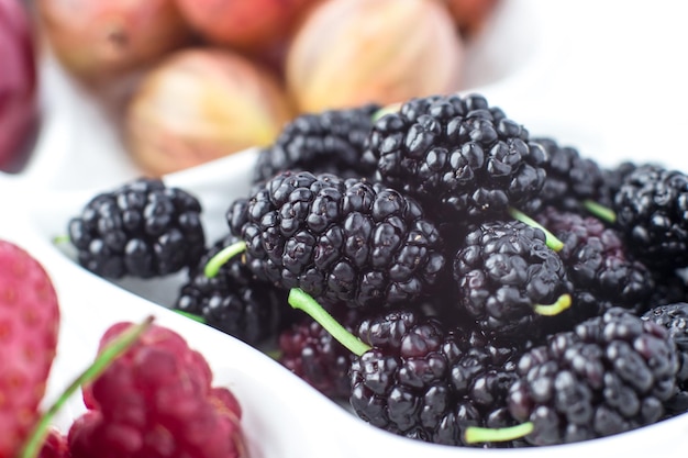 Close-up van moerbei op een fruitschaal op een witte achtergrond Rijpe bessen Vitaminen en een gezonde levensstijl