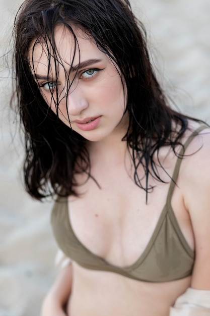 Close-up van mooi luxe slank meisje in zwarte bikini op het oceaanstrand. Sexy gebruind lichaam, platte buik, perfect figuur. Rust op een tropisch eiland. Gouden accessoires. Laagdrempelige foto.