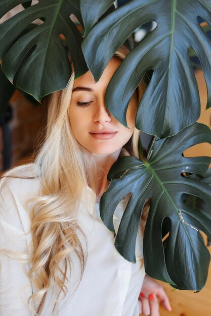 Foto close-up van mooi meisje gezicht overal bladeren groene kamerplant