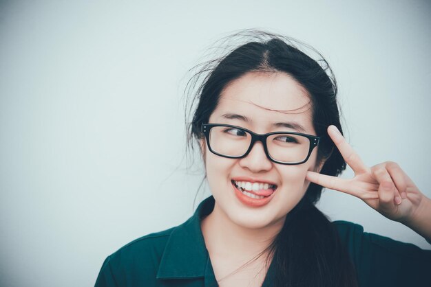 Close-up van mooie aziatische vrouw draagt een bril Thais meisje heel mooi poseert twee vingers op een witte achtergrond
