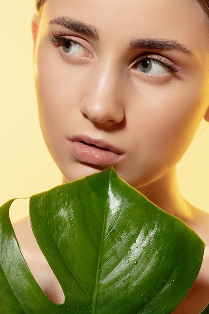 Close up van mooie jonge vrouw met groene bladeren op witte achtergrond.