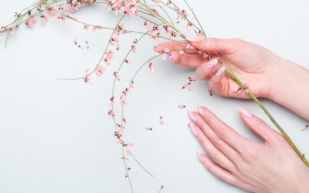 Close-up van mooie vrouwelijke handen met roze bloemen. Handverzorgingsconcept, anti-rimpel, anti-verouderingscrème, spa
