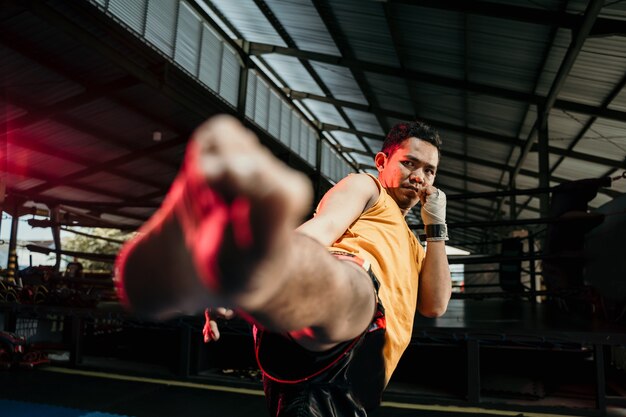 Close up van muay thai bokser in bokshandschoenen maken een middelste trapbeweging in de boksring