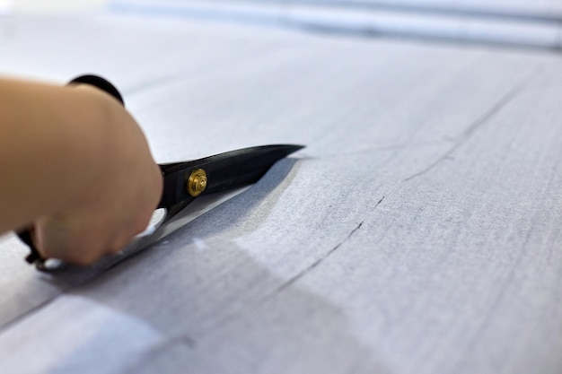 Close-up van naaister snijden stuk stof met een schaar in naaiatelier