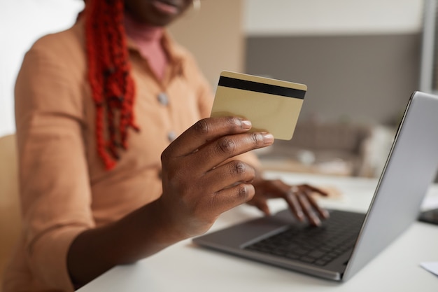 Close-up van onherkenbare Afro-Amerikaanse vrouw met creditcard tijdens het online winkelen vanuit huis laptop, kopieer ruimte