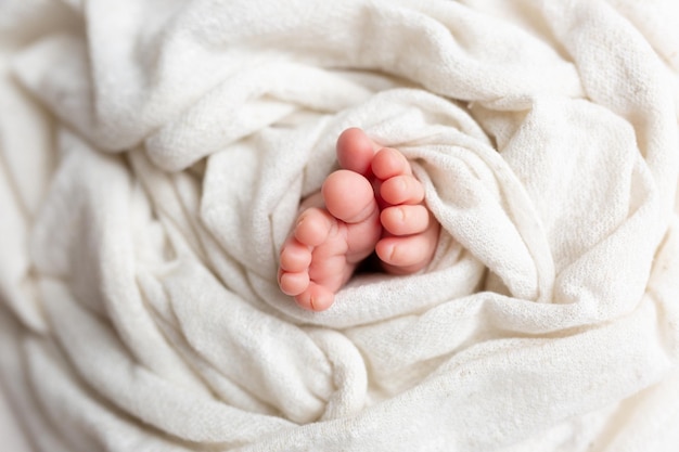 Close-up van onherkenbare schattige baby die voeten schudt terwijl hij in bed ligt, onschuldconcept