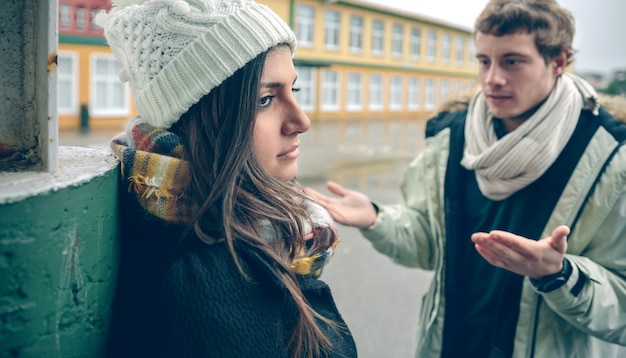 Close up van ontevreden vrouw luisteren argumenten van jonge man tijdens een harde ruzie buitenshuis. Paar relaties en problemen concept.