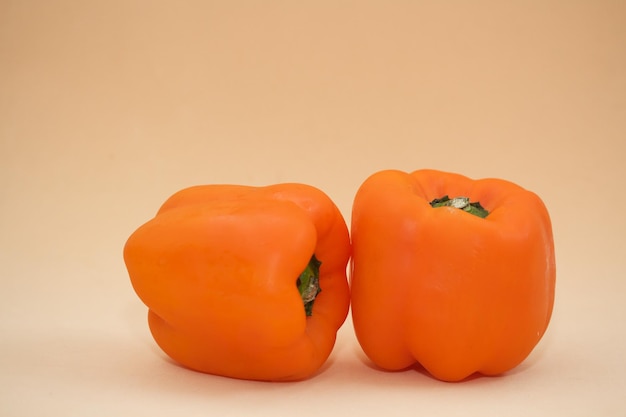 Close-up van oranje paprika tegen een beige achtergrond